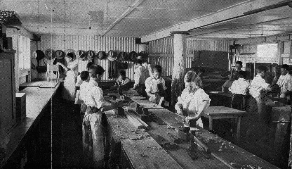 Boys at a long bench planing timber in a school woodworking class, Queensland, 1933